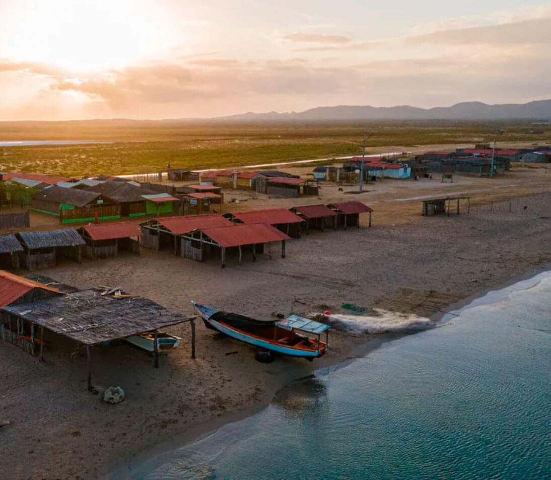 Traditional Wayuu ranchería at dusk with hammocks, desert landscape, and starry sky in Cabo de la Vela