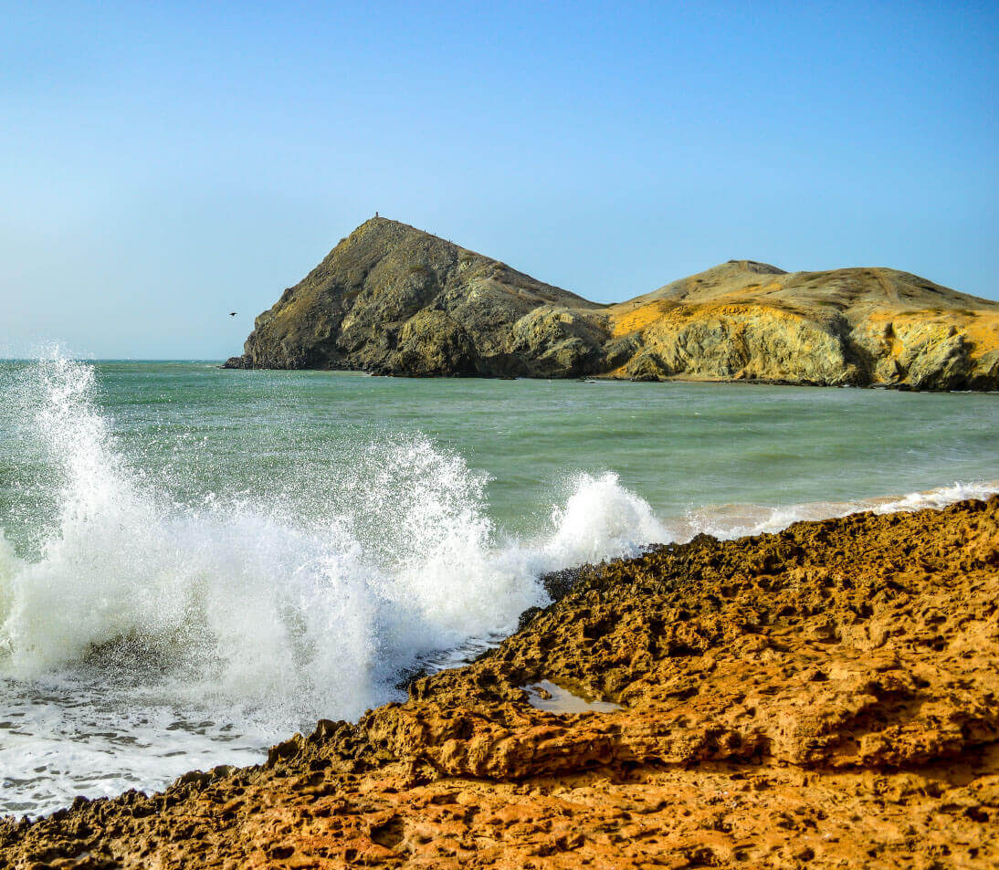 Golden desert landscape of Cabo de la Vela with rustic huts and turquoise Caribbean sea in the background