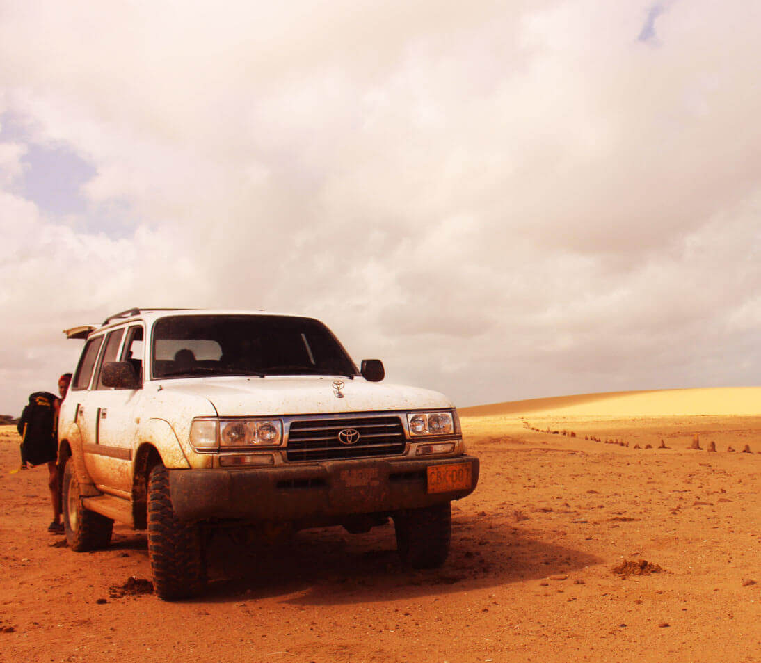 Golden desert landscape of Cabo de la Vela with rustic huts and turquoise Caribbean sea in the background