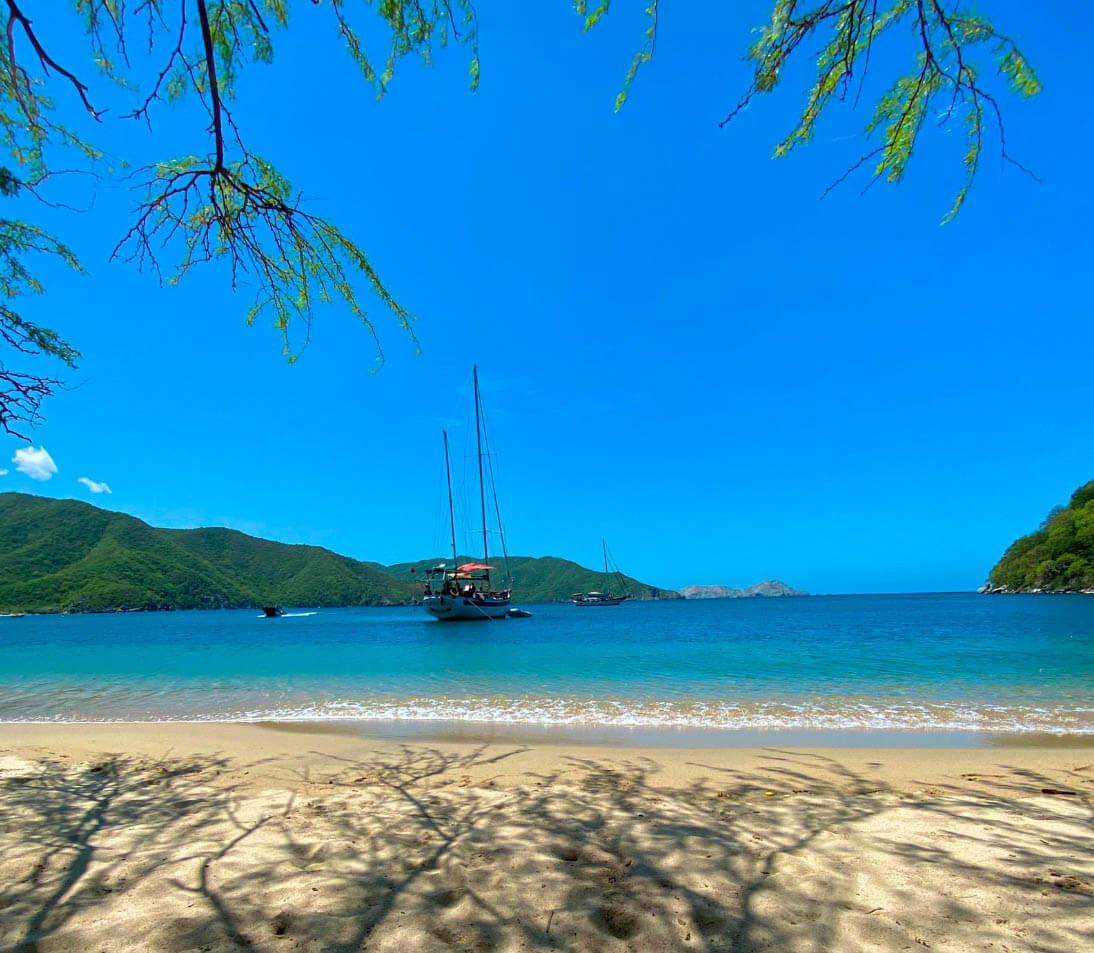 Serene view of Bahía Concha beach showing calm turquoise waters, white sand shoreline, and lush tropical vegetation in Tayrona Park