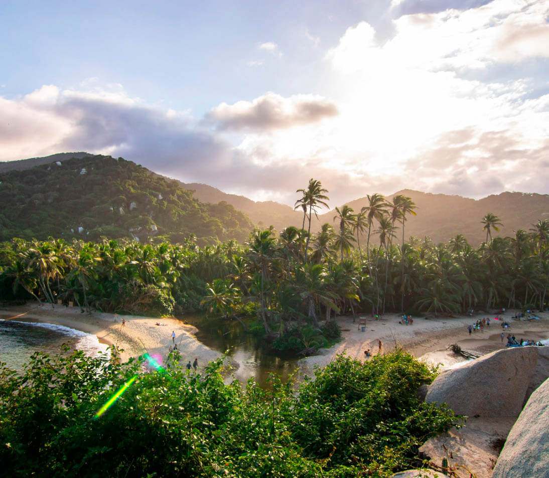 Breathtaking sunset at Cabo San Juan, Tayrona Park, with silhouetted palm trees and hammocks glowing under golden skies