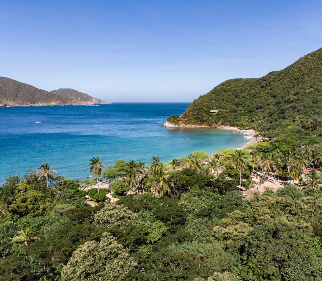 Turquoise waters and white sand at Playa Cristal, Tayrona Park, with vibrant coral reefs visible beneath the surface