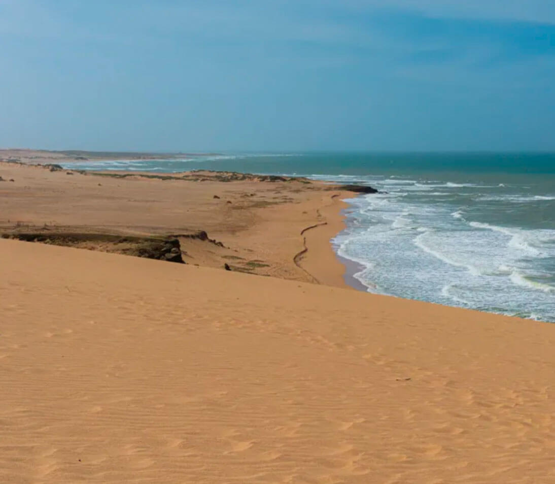 Golden sunset over Punta Gallinas desert with dramatic clouds and silhouetted dunes meeting the Caribbean Sea