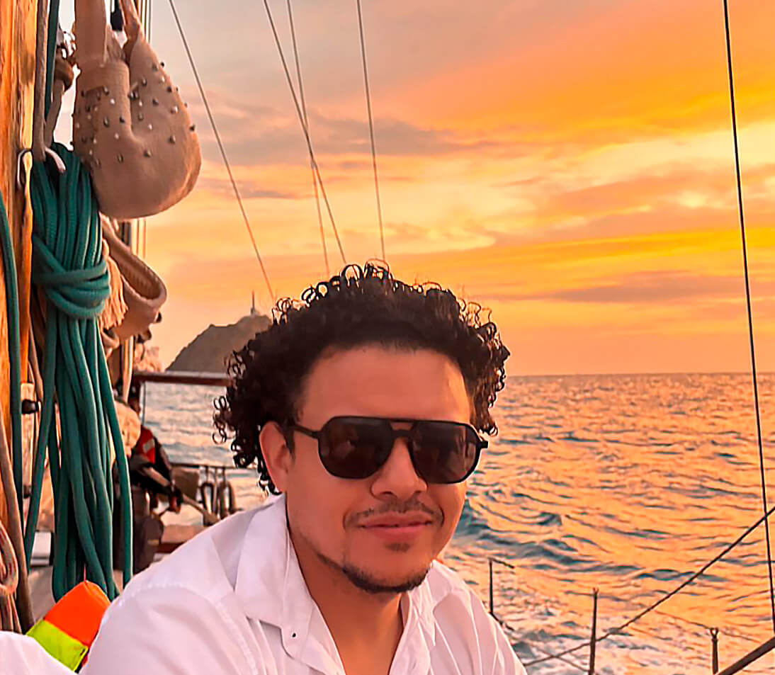 Velero al atardecer frente a las costas de Santa Marta con cielo anaranjado y mar en calma