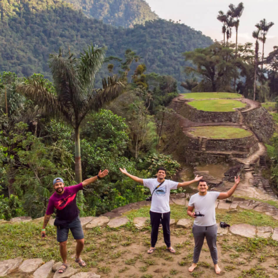 4-Day Lost City Trek - Ultimate Jungle Adventure-trek-4-dias (1) Hiking group resting at ancient stone terraces of Ciudad Perdida with jungle-covered mountains in background