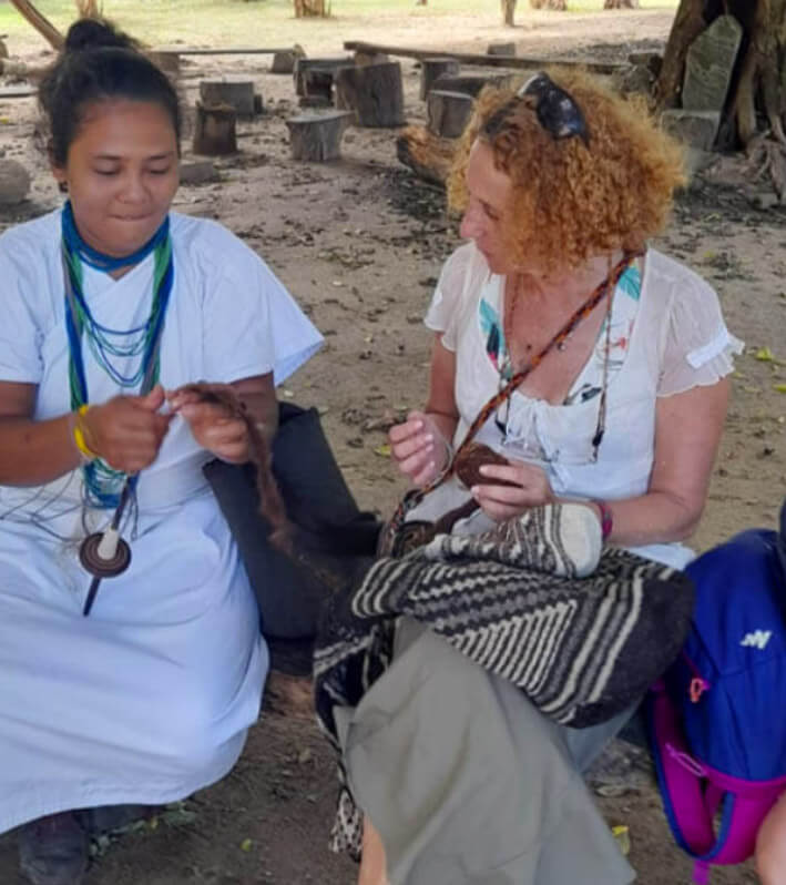 Arhuaca indigenous woman teaching European tourist how to weave traditional mochila bag in Katanzama community