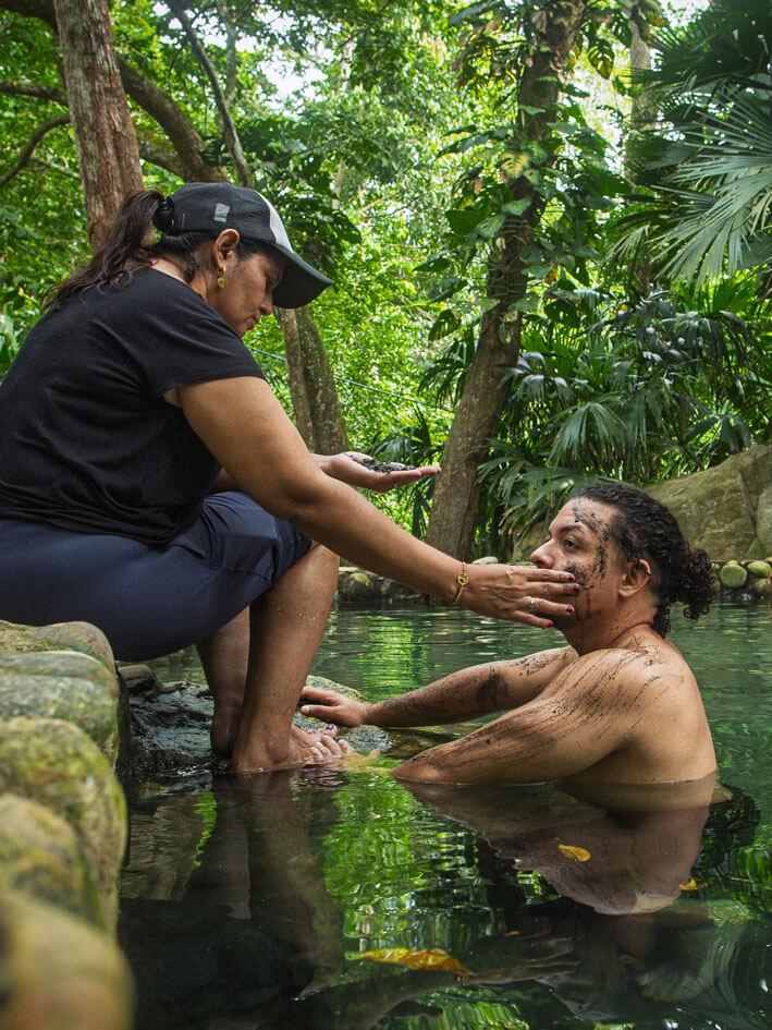 Indigenous spiritual ceremony applying sacred ash to visitor in thermal waters at Bunkuany Chivilongui