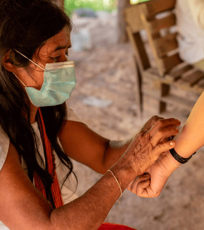 Wiwa indigenous woman placing traditional handmade bracelet on tourist during cultural ceremony in Gotsezhy day tour