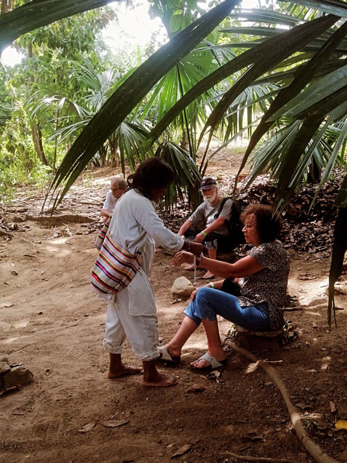 Mamo spiritual leader presenting protective bracelet to visitor during traditional ceremony in Mulkwakungui indigenous community