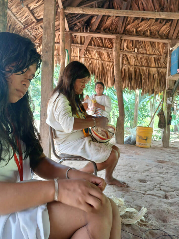 Two indigenous women weaving traditional mochila bags together in Mulkwakungui community workshop