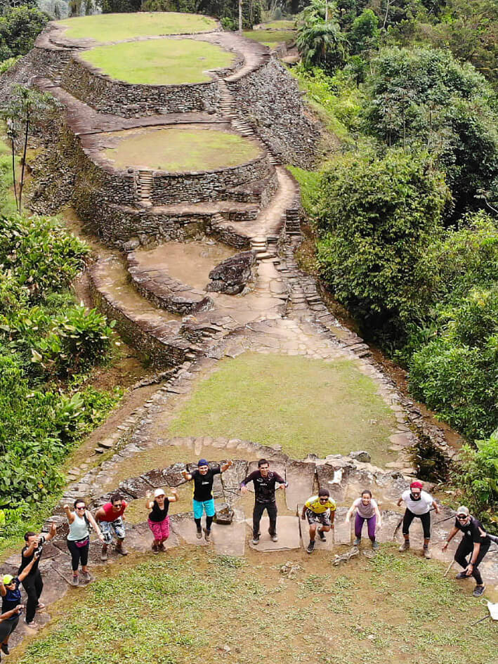 Small group of hikers with indigenous guide at Ciudad Perdida stone terraces at sunrise
